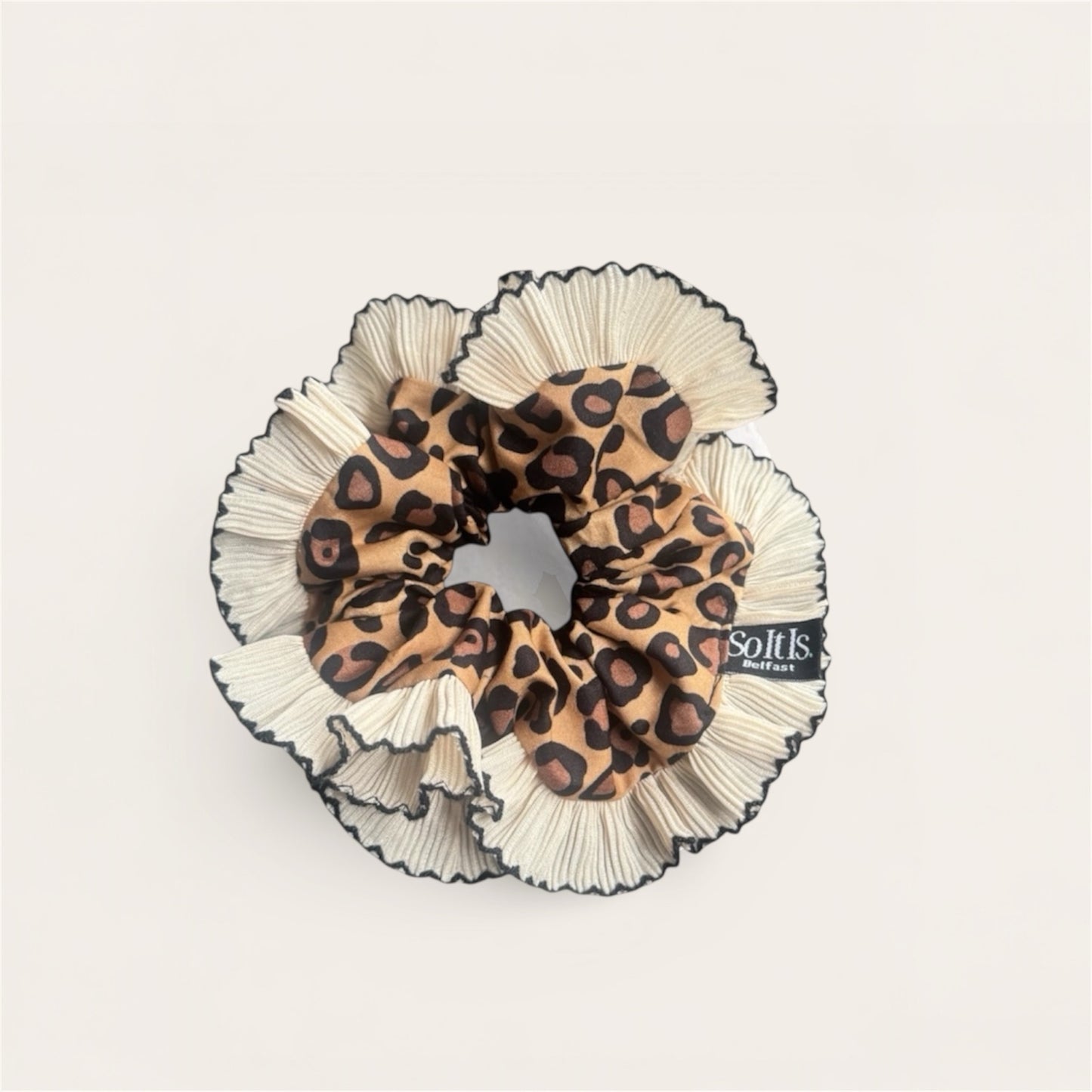 Leopard print scrunchie with cream & black ruffled edges on a light gray background
