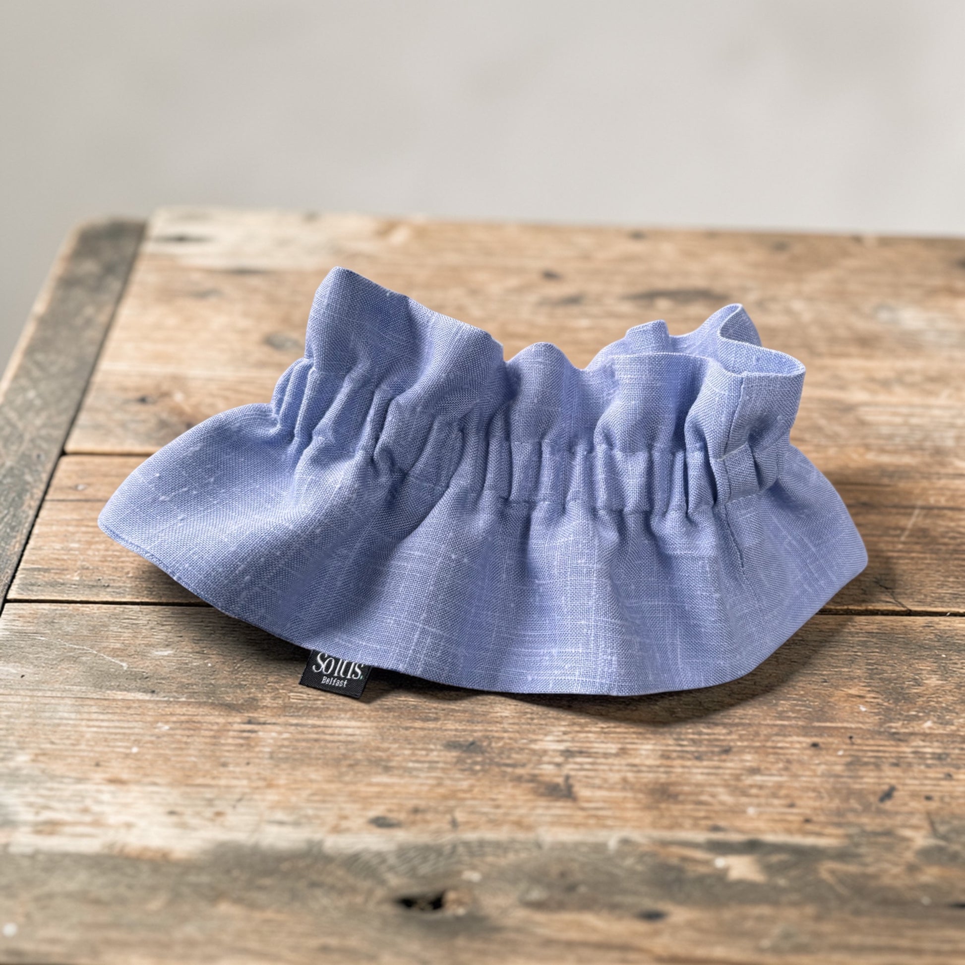 Handmade removable collar in dusty blue Irish linen with gathered ruffle detail on a wooden surface