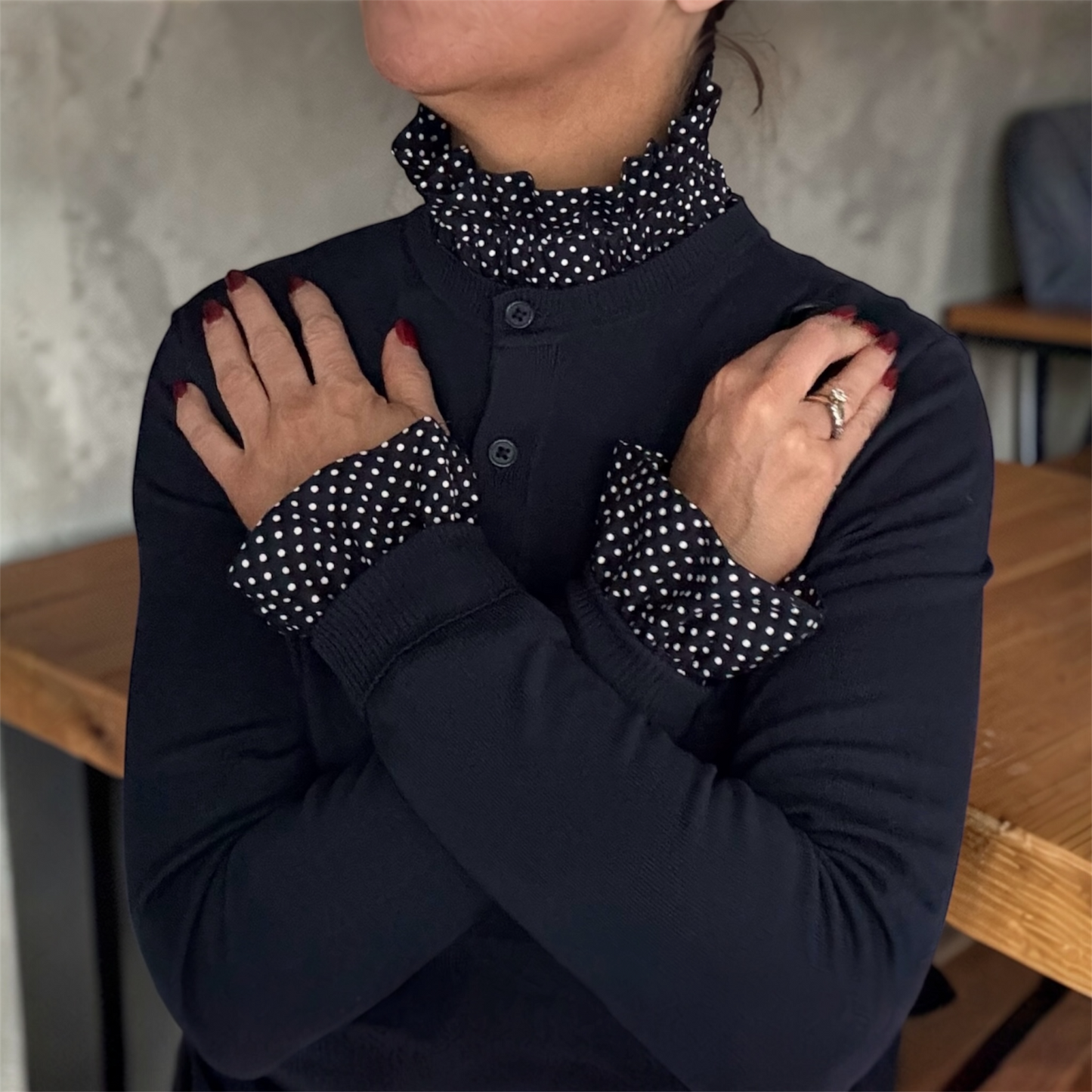 Female wearing a navy blue outfit with polka dot removable cuffs and collar, standing indoors.