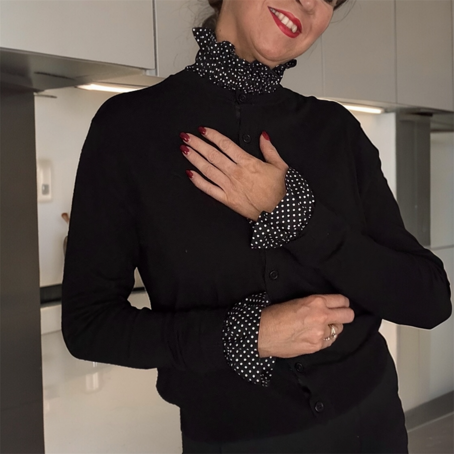 A female wearing a black outfit with black & white polka dot removable cuffs and collar. 